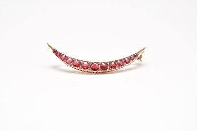 Lot 147 - An Edwardian 9ct gold graduated red paste and diamond set crescent brooch