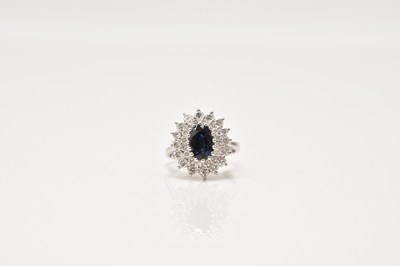 Lot 218 - An 18ct white gold sapphire and diamond oval cluster ring